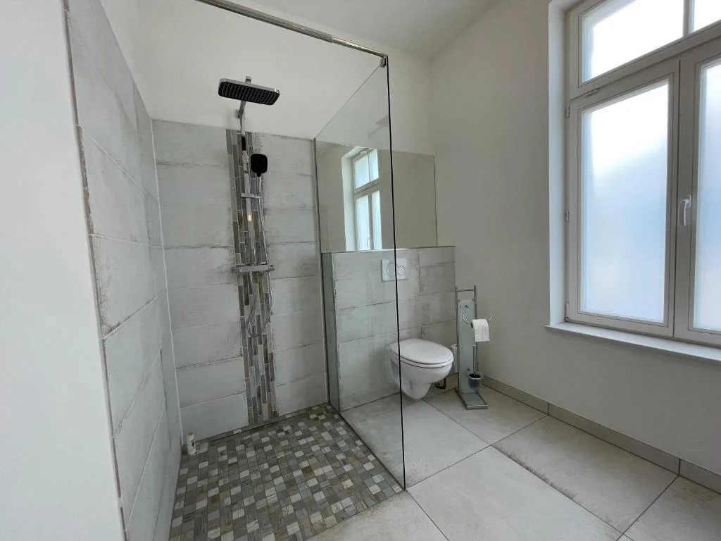 Gemeinschaftsbad der Pension Luisengrün mit ebenerdiger Dusche, Glaswand und Tageslicht
